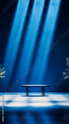A low, dark-wood oval table sits centrally in a dark blue room, bathed in three vertical beams of light. Small, leafy plants flank the table, their shadows cast on the reflective floor.