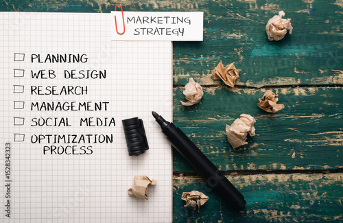 Black marker sits on a piece of paper with a list of marketing strategies