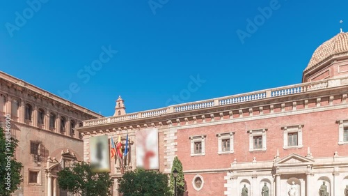 Panorama showing Patriarch's College Square in Valencia timelapse, featuring the historic Museo del Patriarca, fountain with sculptures and Church of the Patriarch. Clear blue sky, Spain.