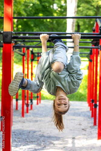 A young girl playing on bars outdoors enjoying an active lifestyle