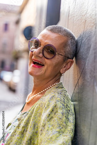 portrait of elegant mature woman smiling looking at camera leaning back against black wall
