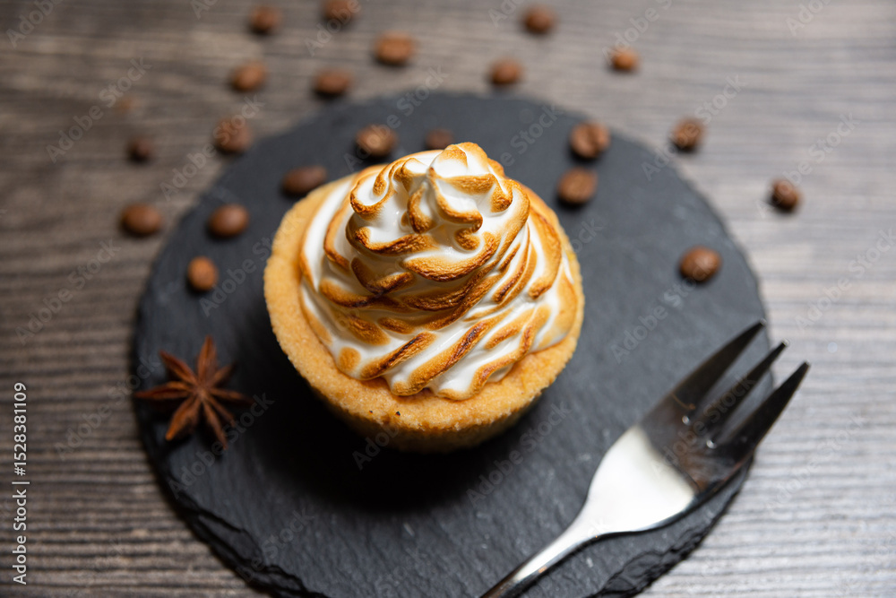 Fototapeta premium Toasted Meringue Tart on Slate with Coffee Beans. Delicious tart topped with golden toasted meringue, presented on a black slate plate with scattered coffee beans and star anise.