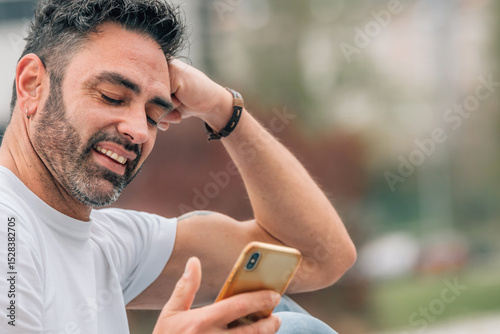 portrait of attractive man with beard outdoors looking at mobile phone