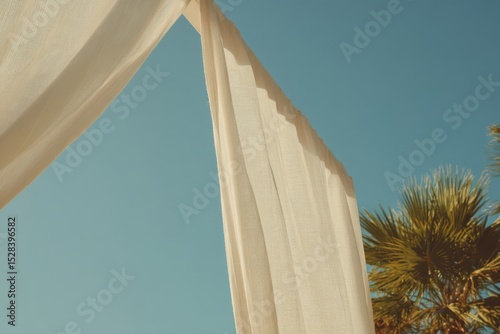 Cozy beach cabana with flowing white linen curtains beside palm trees on a clear sunny day, perfect retreat for relaxation and enjoying the ocean breeze