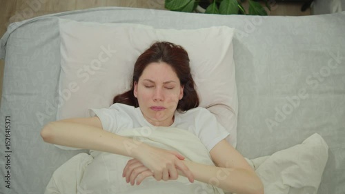 Young adult woman puts down immobile numb hand after sleep because of sleeping with a stretched arm