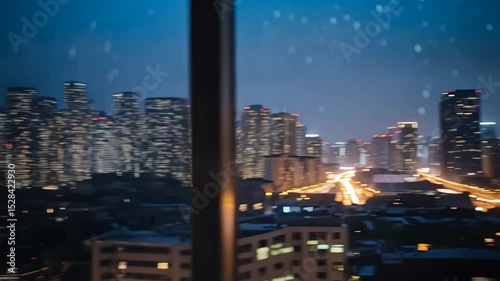 Raindrops on window with blurred city skyline at night featuring distant glowing buildings and busy illuminated highway traffic.