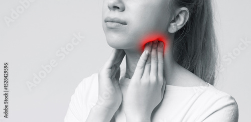 Young woman suffering from tonsillitis, pulping her neck, monochrome panorama photo, free space photo