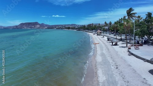 Aerial La Paz Mexico ocean beach low 2. Capital Mexican state of Baja California Sur, peninsula. Ferry, fishing, cargo and cruise ships. Beach Malecon markets. Eco tourism economy.