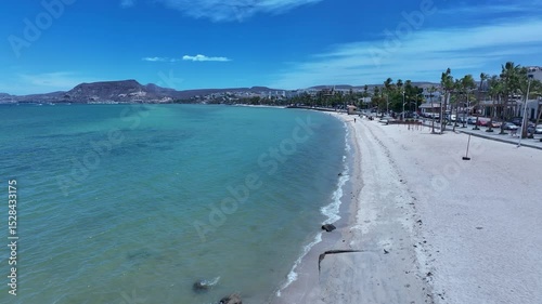 Aerial La Paz Mexico ocean beach low 1. Capital Mexican state of Baja California Sur, peninsula. Ferry, fishing, cargo and cruise ships. Beach Malecon markets. Eco tourism economy.