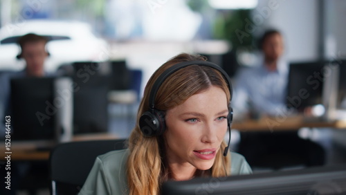 Help desk specialist talking on headset working computer at office closeup.