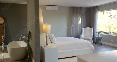 Camera pausing on bathtub faucet, panning right to reveal king bed, armchair, plant in master suite