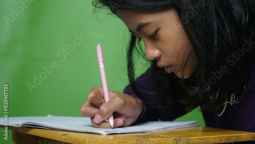Girl is writing in book, making notes on a diary, green color background