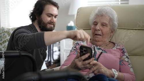 A grandmother and her grandson enjoy a joyful moment as they share photos on a smartphone, celebrating family memories and happiness in a cozy living space.
