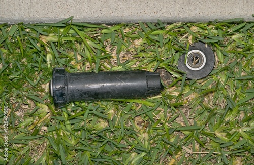 Broken sprinkler head nozzle on lawn from lawnmover accident backyard garden.