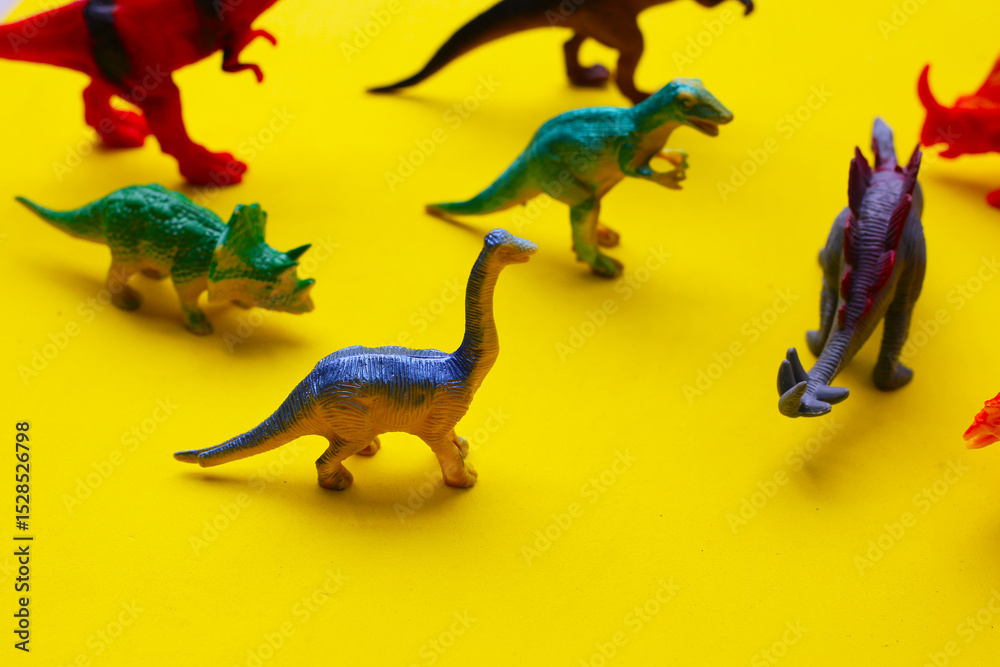 Fototapeta premium Plastic dinosaur toys on yellow background