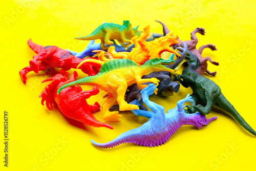 Plastic dinosaur toys on yellow background photo