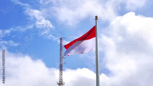 The red and white flag flutters in the wind with a blue sky background