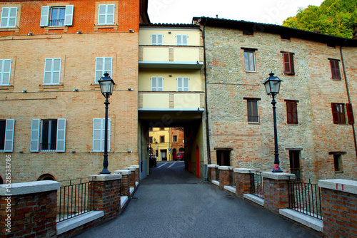 Fototapeta Naklejka Na Ścianę i Meble -  COMUNANZA, ITALY - AUGUST 14, 2022: Streets of Comunanza. Scenic entrance to Comunanza welcomes visitors with a bridge, charming streets, lanterns, and a blend of tradition and tranquility