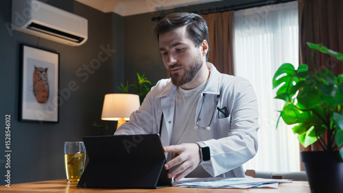 Doctor in a white coat prepares for patient consultations, using a tablet to review information, exuding professionalism and focus in their medical role.