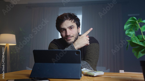 Man pointing while working on tablet at home