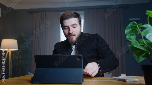Man using tablet at desk with money