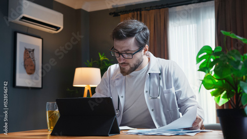Focused doctor working on tablet at home