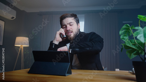 Busy businessman on phone checking time at desk
