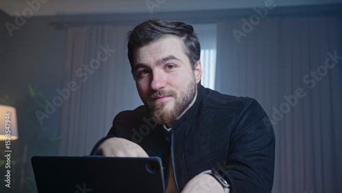 Confident man smiling while working on laptop