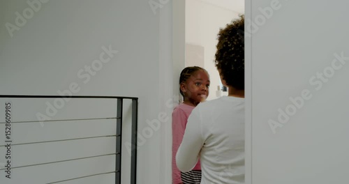 Entering hallway, mother and daughter marking height on doorframe with ruler and pencil for growth