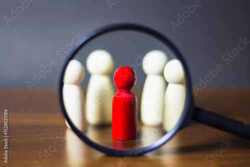 Concept search for business leadership, businessman, qualified personnel, hand holding magnifying glass, focus on wooden doll