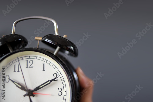 Papier peint Closeup Of Hand Holding Classic Alarm Clock Against Grey Background