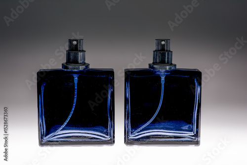 Blue spray bottle on graduated background glass aftershave bottle showing pump and spray