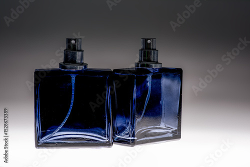 Blue spray bottle on graduated background glass aftershave bottle showing pump and spray