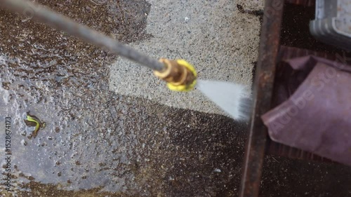 Cleaning cement backyard with power washer.	