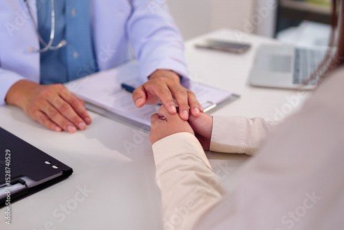 Doctor's Comforting Hand: A doctor gently holds a patient's hand, offering comfort and reassurance during a consultation.  The image conveys empathy and trust in the patient-doctor relationship.