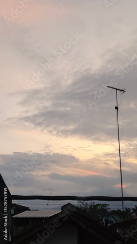 scenery of the gray sky with the roofs of houses and antenna