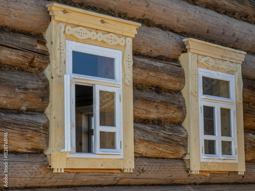 An old wooden log house built in the 19th century. The windows in the village house. Life in the countryside. The history and traditions of rural life.