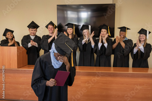 Happy African woman in hijab receiving diploma and classmates applauding her. 