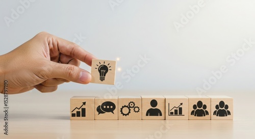 Hand arranging wooden blocks with icons representing business growth and planning strategy 