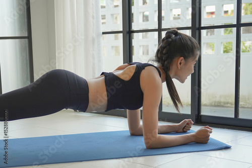 Asian woman in sportswear pranking on yoga mat in living room