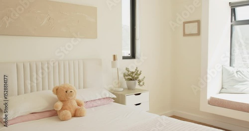 On shot start, camera is panning left inward to focus on teddy bear centered on bed