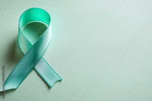 Green ribbon on a light green background, a symbol of cancer awareness and support for people living with cancer. The stock photo includes terms related to healthcare and education.