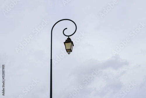 Vintage lamp post stands elegantly against a cloudy sky in a charming urban setting