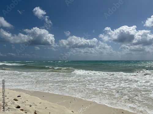 Fototapeta Naklejka Na Ścianę i Meble -  Sunny day at Playa del Carmen with turquoise waves, white sand, and dramatic clouds over the Caribbean Sea's scenic coastline.