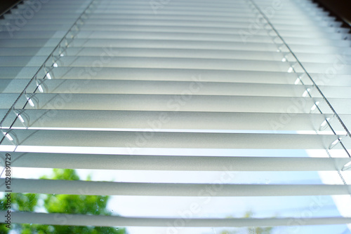 Interior pattern: horizontal stripes of open blinds photographed from bottom to top. Options for protecting an apartment from sunlight: pleated blinds. Background with an everyday item.