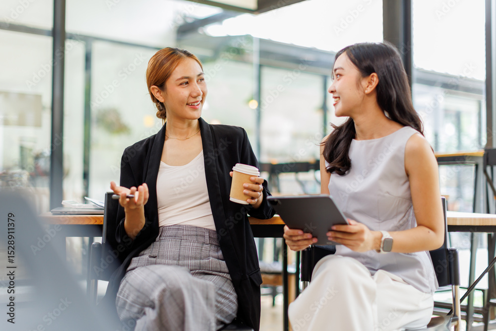 Fototapeta premium Young Asian business two women explain working together using documents tablet at the office. 