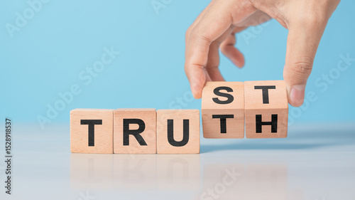Hand flipping wooden cube with TRUST and TRUTH words. Concept of business ethics, honesty, integrity, and building trustworthy relationships. Clean table background
