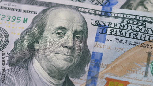 A closeup view of a one hundred dollar bill prominently featuring the portrait of Benjamin Franklin