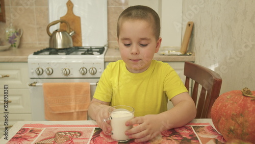 A Young Boy Happily Enjoying a Glass of Refreshing Milk While at Home with Family