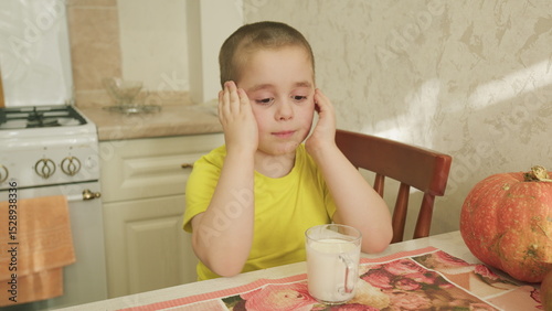 A cheerful child sitting comfortably at a table in a cozy kitchen drinking milk and enjoying life